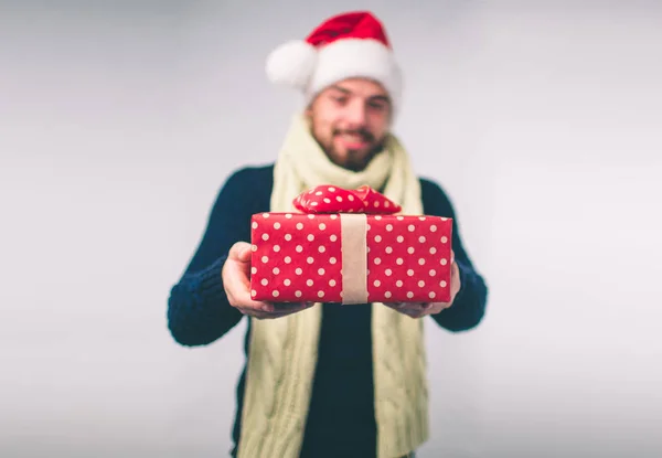 Hombre guapo en un sombrero de Navidad sosteniendo regalos sobre fondo blanco — Foto de Stock