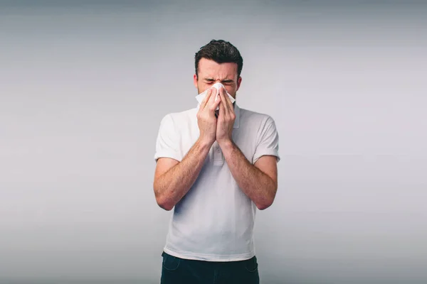 Photo de studio d'un jeune homme avec mouchoir. Le malade isolé a le nez qui coule. homme fait un remède pour le rhume commun.Nerd porte des lunettes — Photo