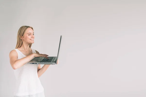 O femeie care ţine laptopul izolat pe gri. Fata in camasa alba, studio shot — Fotografie, imagine de stoc