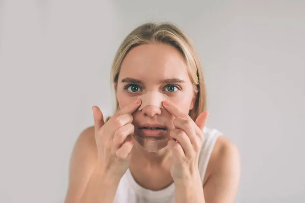 Viso di donna che guarda la fotocamera applicare l'intonaco sotto l'occhio durante la procedura di trucco, isolato su sfondo bianco. Vista orizzontale — Foto Stock