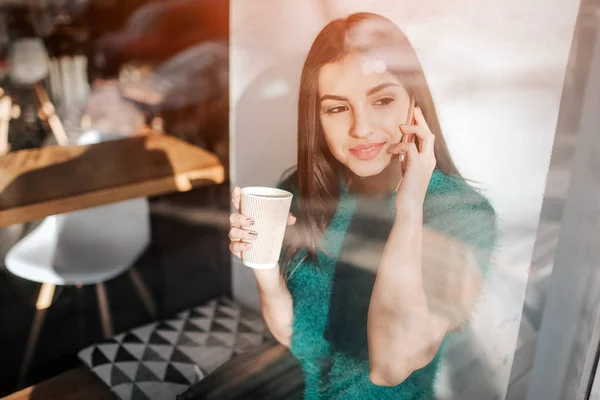 年轻美丽的女人在咖啡馆酒吧喝咖啡。女性模特年轻使用智能手机在咖啡馆 — 图库照片