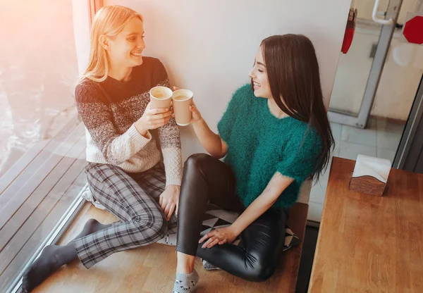 Két fiatal nő beszélget egy kávézóban. Két jó barát együtt élvezik a kávé — Stock Fotó