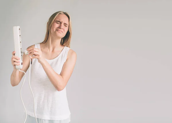 Улыбающаяся счастливая женщина с помощью разъема вытащить розетку, показывая сохранение электрической концепции изолированы на фоне стены с одеждой образа жизни — стоковое фото
