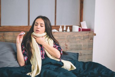 Kadın yatakta yatan gribi virüsü ile o bir termometre ve alnına dokunmak onun Sıcaklığı ölçme.