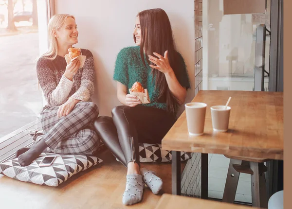 Két fiatal nő beszélget egy kávézóban. Két jó barát együtt élvezik a kávé. — Stock Fotó