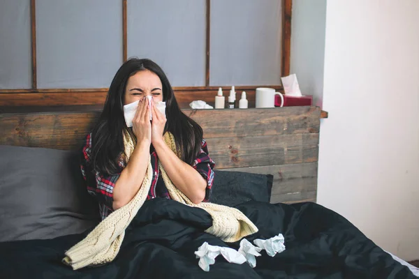 Imagen de una hermosa mujer en la cama con pañuelo. La modelo femenina enferma tiene secreción nasal. Chica hace una cura para el resfriado común . — Foto de Stock