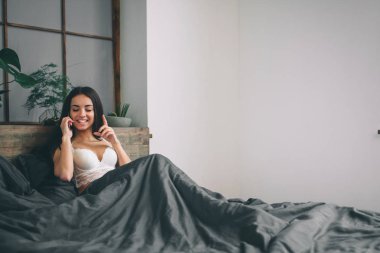 Güzel seksi esmer kadın telefonla konuşuyor yatakta yalan
