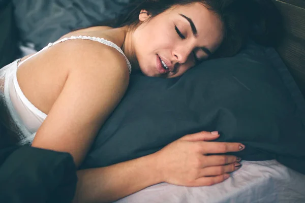 Vista lateral de la hermosa joven sonriendo mientras duerme en su cama en casa —  Fotos de Stock