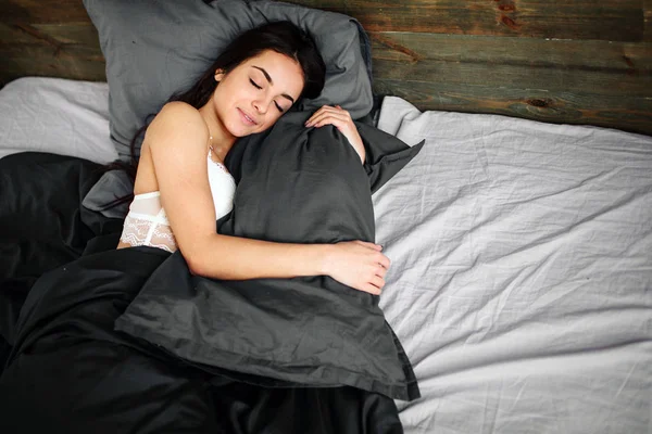 Pandangan samping wanita muda yang cantik tersenyum saat tidur di tempat tidurnya di rumah — Stok Foto