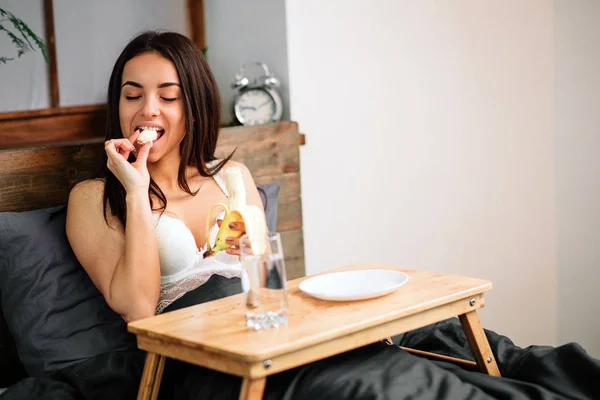 Jovem bela mulher tomando café da manhã na cama — Fotografia de Stock