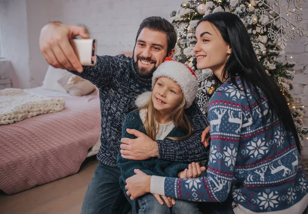 Sourire jeune famille dans l'atmosphère de Noël faire des photos avec smartphone — Photo