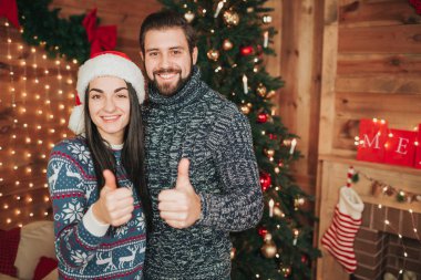 Mutlu Noeller ve mutlu yeni yıl. Genç çift evde tatil kutluyor. İki mutlu wan ve onların başparmak tutan kadın