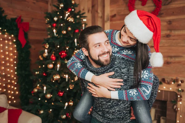 Frohe Weihnachten und ein gutes neues Jahr. junges Paar beim Urlaub zu Hause. Mann gibt Frauen Huckepack — Stockfoto