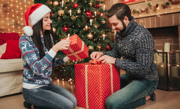 Frohe Weihnachten und ein gutes neues Jahr. junges Paar beim Urlaub zu Hause. Mann und Frau packen Geschenke aus — Stockfoto