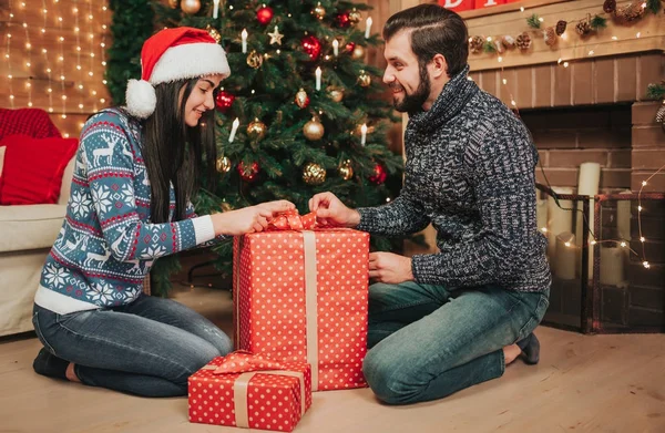Frohe Weihnachten und ein gutes neues Jahr. junges Paar beim Urlaub zu Hause. Mann und Frau packen Geschenke aus — Stockfoto
