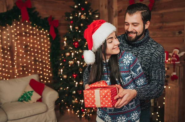 Frohe Weihnachten und ein gutes neues Jahr. junges Paar beim Urlaub zu Hause. glücklicher junger Mann und Frau umarmen und beschenken einander — Stockfoto