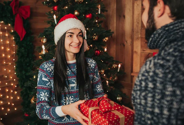 Frohe Weihnachten und ein gutes neues Jahr. junges Paar beim Urlaub zu Hause. glücklicher junger Mann und Frau, die einander Geschenke machen. — Stockfoto