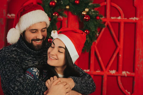 Feliz Navidad y Feliz Año Nuevo. Pareja joven celebrando vacaciones en casa. Feliz joven hombre y mujer abrazan y se dan regalos — Foto de Stock