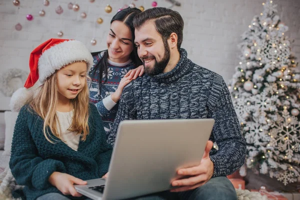 Joyeux Noël et Joyeuses Fêtes Joyeux maman, papa et sa fille mignonne fille à utiliser un ordinateur portable. Parent et petit enfant s'amusent près de l'arbre de Noël à l'intérieur. Bonjour, Noël. Portrait famille close up — Photo