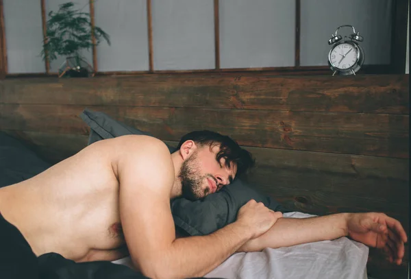 Портрет подходящего мужчины, спящего в роскошной спальне, купающегося в ярком теплом утреннем свете окна — стоковое фото