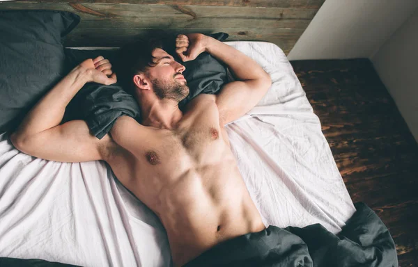 Retrato de ajuste modelo masculino dormindo no quarto luxuoso banhado em luz de janela de manhã quente brilhante — Fotografia de Stock