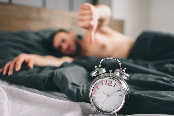 Hora de acordar. Um homem cansado na cama não está feliz. maduro cara segurando despertador ao verificar o tempo para o trabalho — Fotografia de Stock