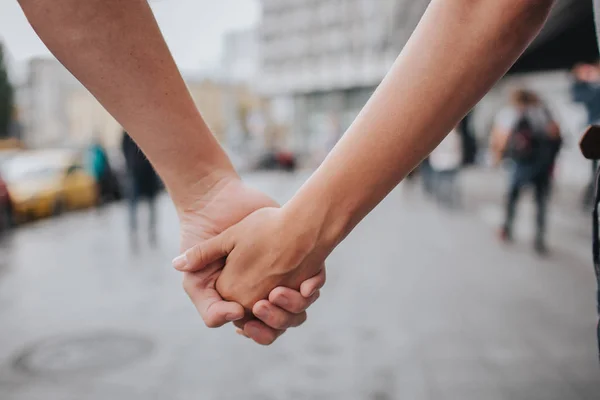 Un par de manos cerradas al aire libre en el amor y la relación romántica. Cierra el cuerpo. hombre y mujer en la ciudad . — Foto de Stock