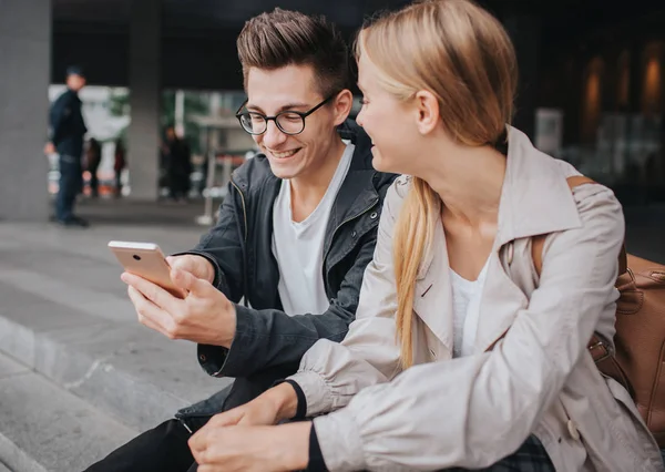 Paar oder Freunde lachen lustig und haben Spaß mit einem Smartphone in einer Großstadt Straße. — Stockfoto