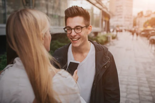 Pareja o amigos riendo divertido y divertirse con un teléfono inteligente en una calle de la gran ciudad . — Foto de Stock