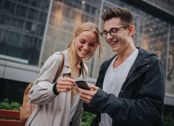 Paar oder Freunde lachen lustig und haben Spaß mit einem Smartphone in einer Großstadt Straße — Stockfoto