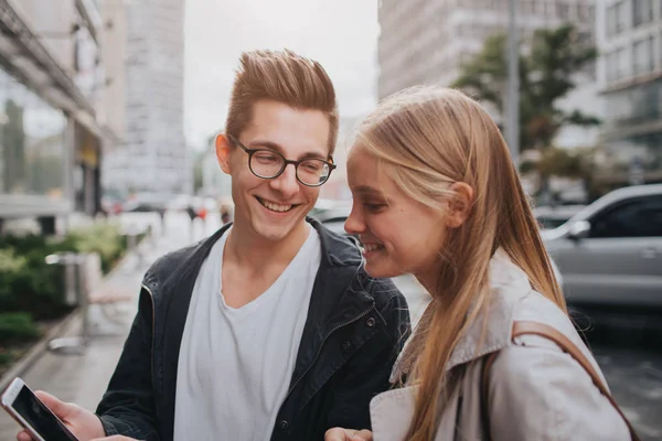 Pareja o amigos riendo divertido y divertirse con un teléfono inteligente en una calle de la gran ciudad — Foto de Stock