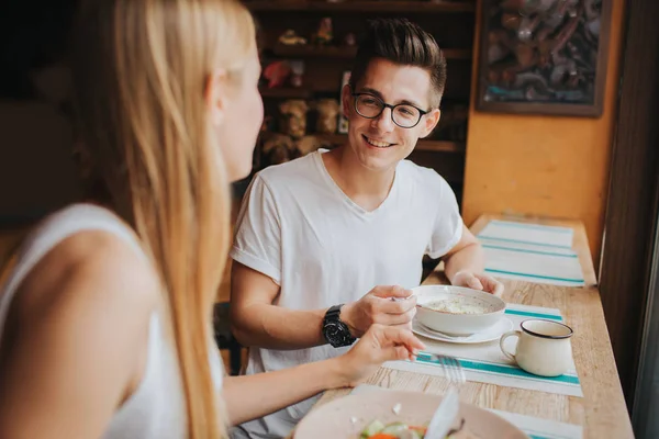 Gelukkige jonge paar in liefde met een mooie datum in een bar of restaurant. Zij sommige verhalen te vertellen over zichzelf, thee of koffie drinken en en eten salade en soep. — Stockfoto