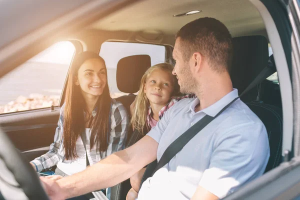 Família feliz em uma viagem de carro. Pai, mãe e filha estão viajando pelo mar ou pelo oceano ou pelo rio. Passeio de verão de automóvel — Fotografia de Stock