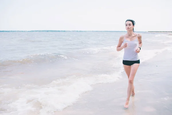 Hermosa mujer corriendo al atardecer. Joven modelo de fitness cerca de la playa. Vestido con ropa deportiva . —  Fotos de Stock