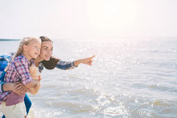Feliz familia en la playa. Gente divirtiéndose en vacaciones de verano. Padre, madre e hijo contra el fondo azul del mar y del cielo. Concepto de viaje — Foto de Stock
