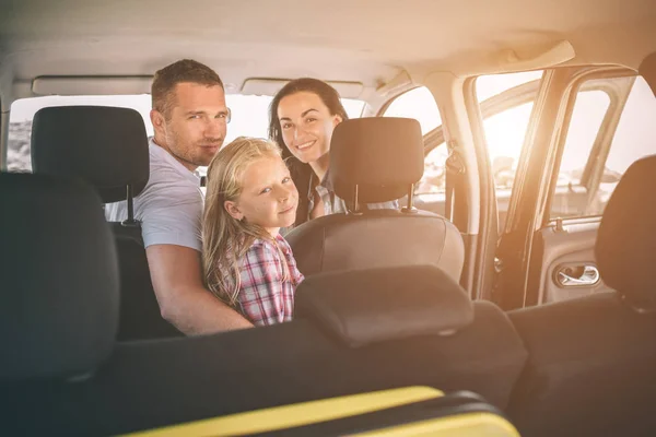 Happy family on a road trip in their car. Dad, mom and daughter are traveling by the sea or the ocean or the river. Summer ride by automobile