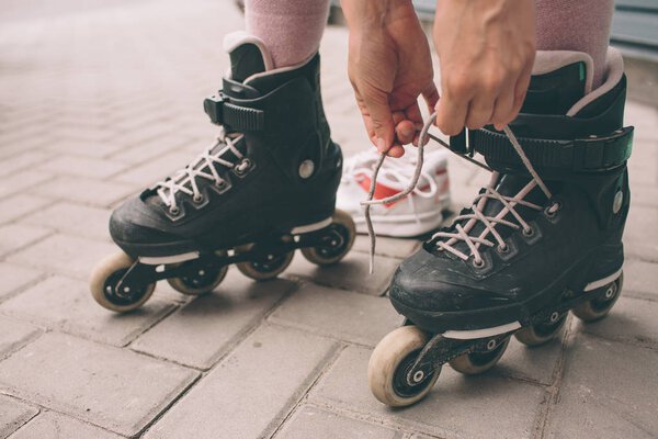 Pretty brunette girl posing with roller skates outdoors. Summer lifestyle portrait