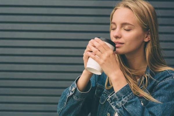 Mooi meisje zit in de straat met koffie in de ochtend en ontspannen. — Stockfoto