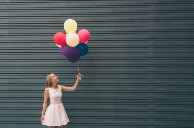 Gri - açık havada yaz konsepti yakınında bir sokakta renkli balonlar ile mutlu genç kadın