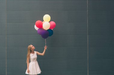 Mutlu genç kadın gri duvar - açık havada yaz konsepti yakınında bir sokakta renkli balonlar ile