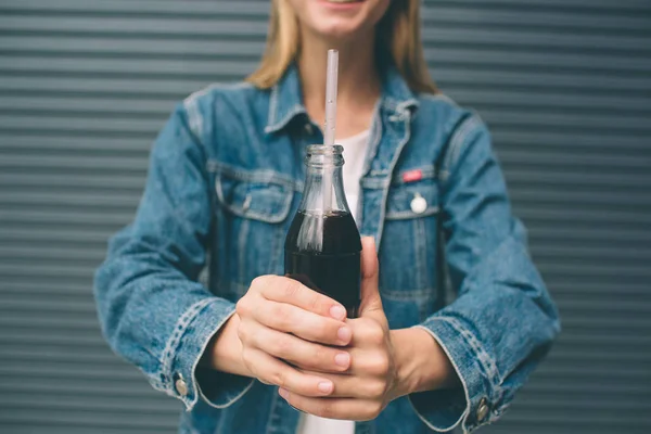 Bebidas, pessoas e conceito de estilo de vida - close-up de mulher feliz beber cola com palha perto da parede cinza — Fotografia de Stock