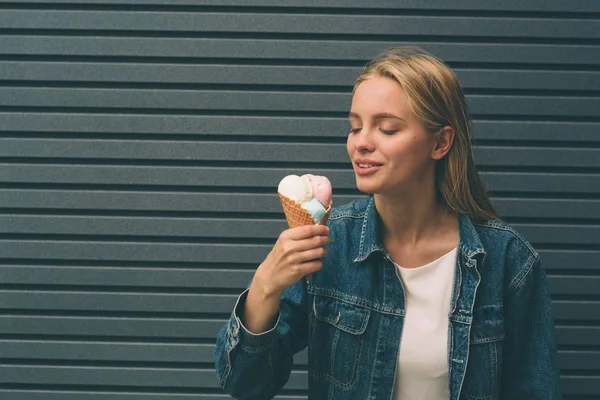 年轻快乐的女孩吃冰激淋，室外，在背景蓝色墙上的肖像 — 图库照片