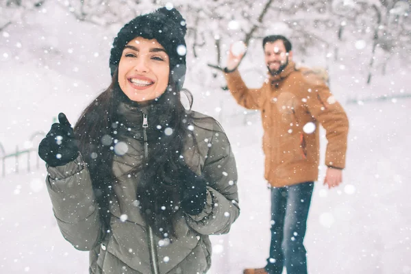 冬の幸せな若いカップル。屋外の家族。男と女の上方への検索と笑っています。愛、喜び、シーズン、冬の公園を歩いて人々。雪だるま式に彼は — ストック写真