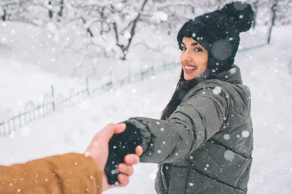 Joyeux jeune couple en hiver. Famille En plein air. homme et femme regardant vers le haut et riant. L'amour, le plaisir, la saison et les gens - marcher dans le parc d'hiver. Tenez-vous et tenez-vous la main — Photo