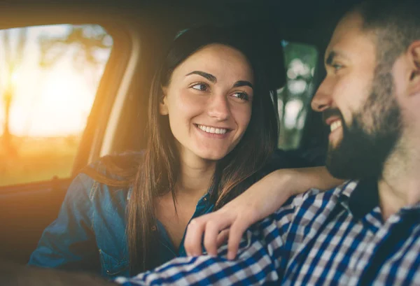 Conduce con cuidado. Hermosa pareja joven sentada en los asientos delanteros del pasajero y sonriendo mientras un hombre guapo conduce un coche . — Foto de Stock