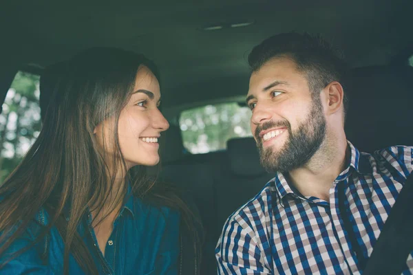 Осторожно за рулем. Красивая молодая пара сидит на переднем пассажирском сиденье и улыбается, пока красивый мужчина водит машину . — стоковое фото