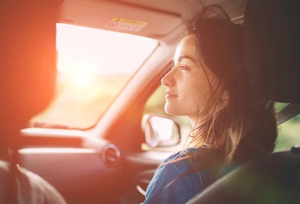 Hermosa mujer sonriendo mientras se sienta en los asientos delanteros del pasajero en el coche — Foto de Stock