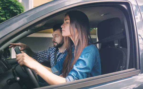 Test de conduite. Jeune femme sérieuse conduisant une voiture se sentant inexpérimenté, regardant nerveusement la circulation routière pour obtenir des informations pour prendre les décisions appropriées. L'homme est un instructeur, contrôlant et vérifiant — Photo