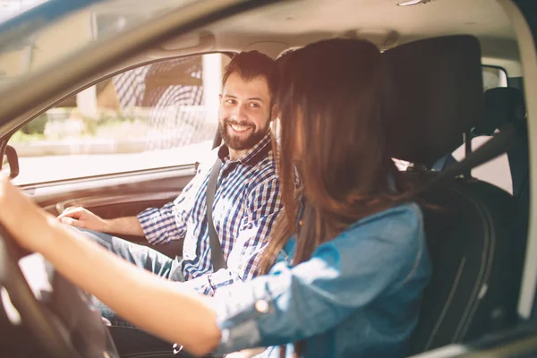 小心驾驶美丽的年轻夫妇坐在前排乘客座椅和微笑, 而女人驾驶汽车 — 图库照片