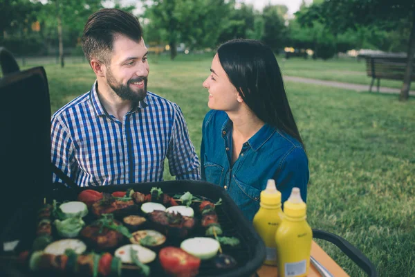 Друзья готовят барбекю и обедают на природе. Пара весело провести время во время еды и питья на пикник - Счастливые люди на барбекю . — стоковое фото